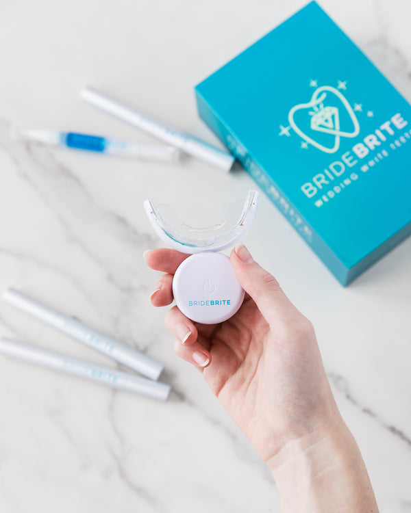 BrideBrite teal whitening kit box with gel pens and LED mouthpiece on marble
