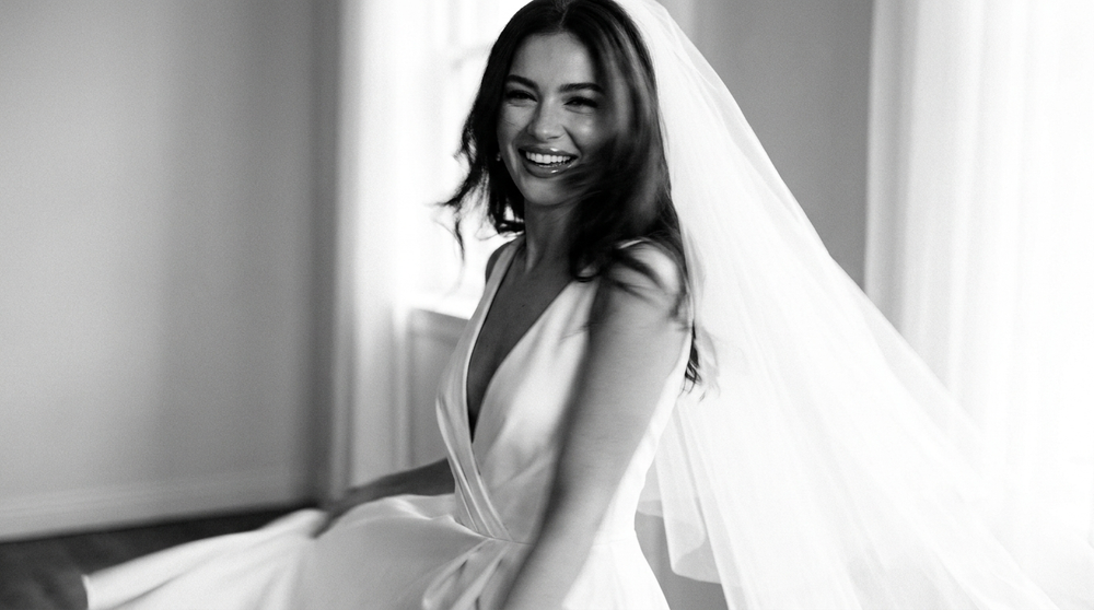 Bride in her wedding dress and veil smiling with a bright white smile on her wedding day